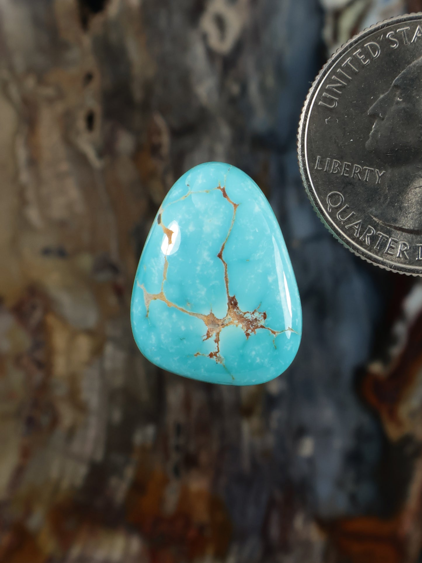 Turquoise cabochon gemstone with light blue base and golden veined matrix