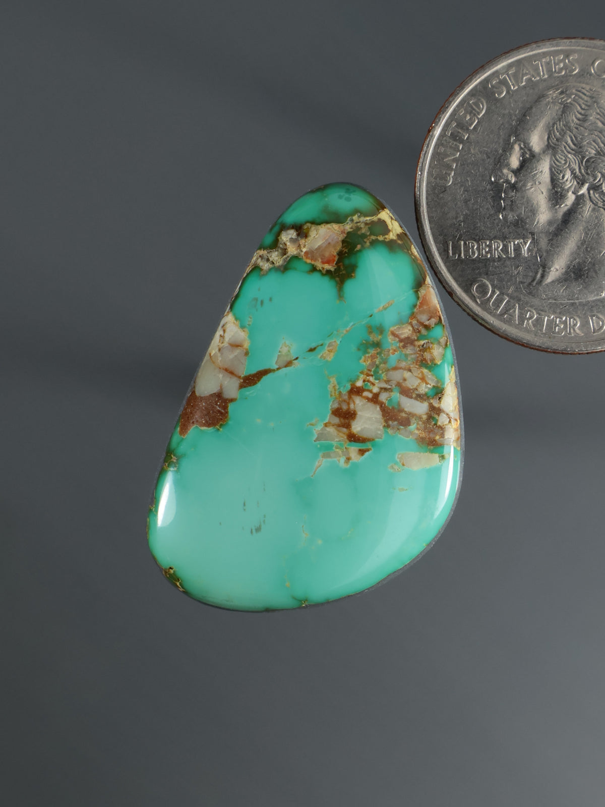 Turquoise teardrop cabochon with gold-brown matrix veining, domed polished stone