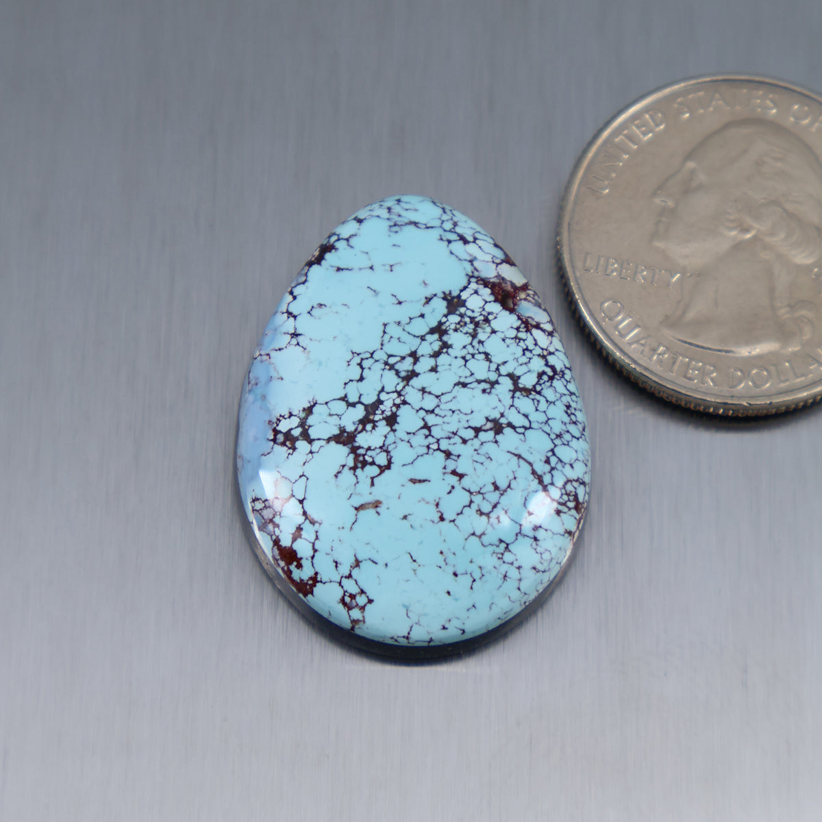 Oval turquoise cabochon with blue surface and red matrix webbing
