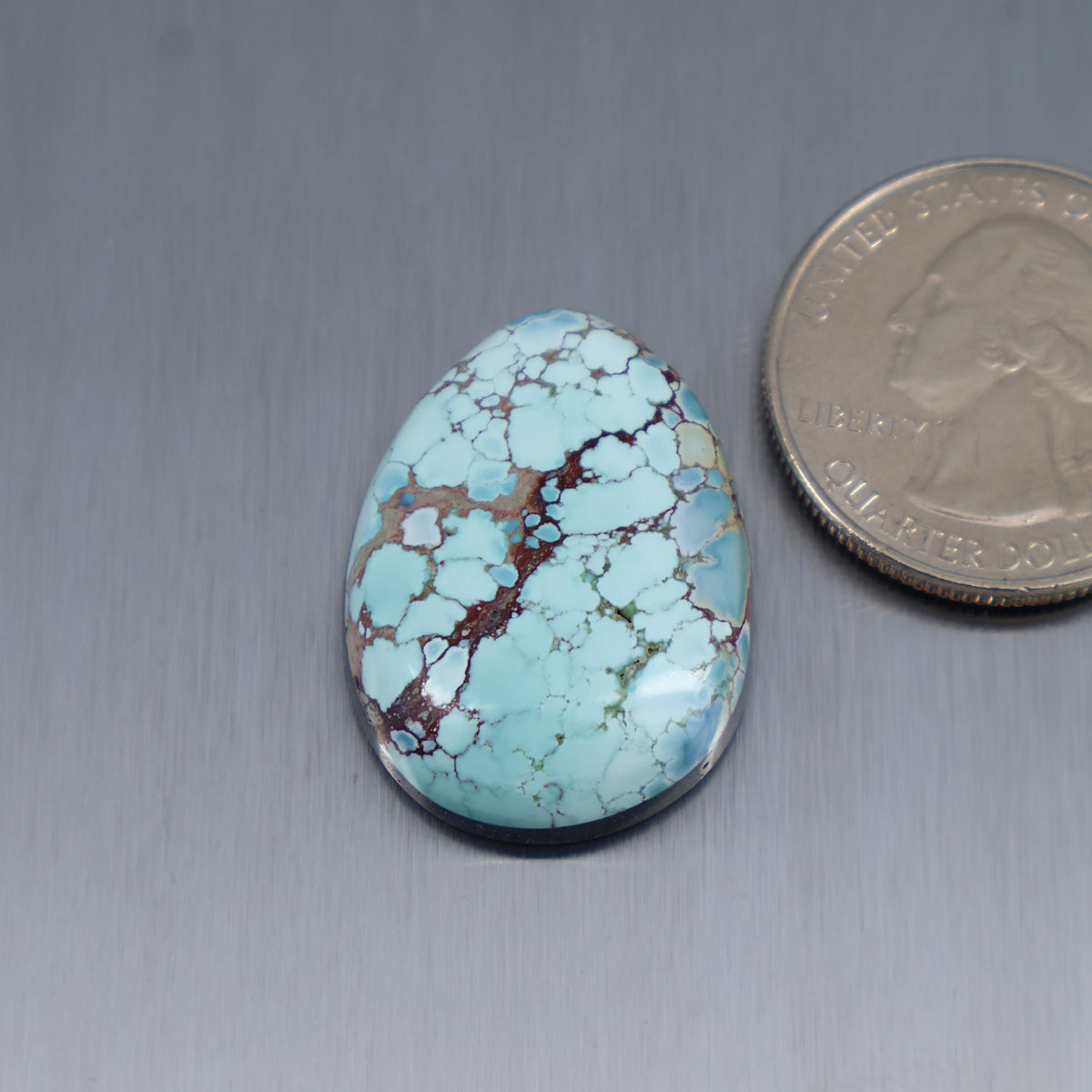 Oval turquoise cabochon gemstone with maroon-brown matrix veining