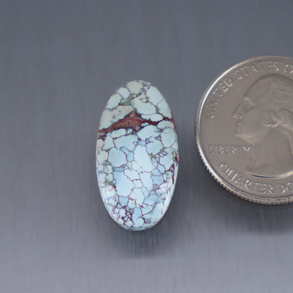 Oval turquoise cabochon with white and blue matrix and reddish-brown patch