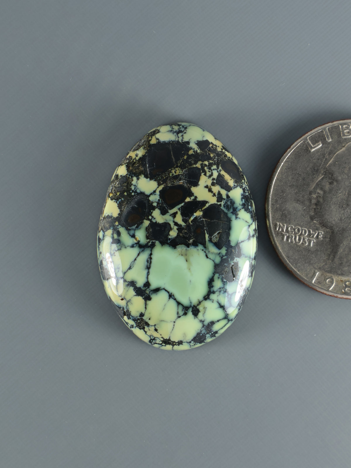 Oval green variscite cabochon with black web pattern, polished stone.