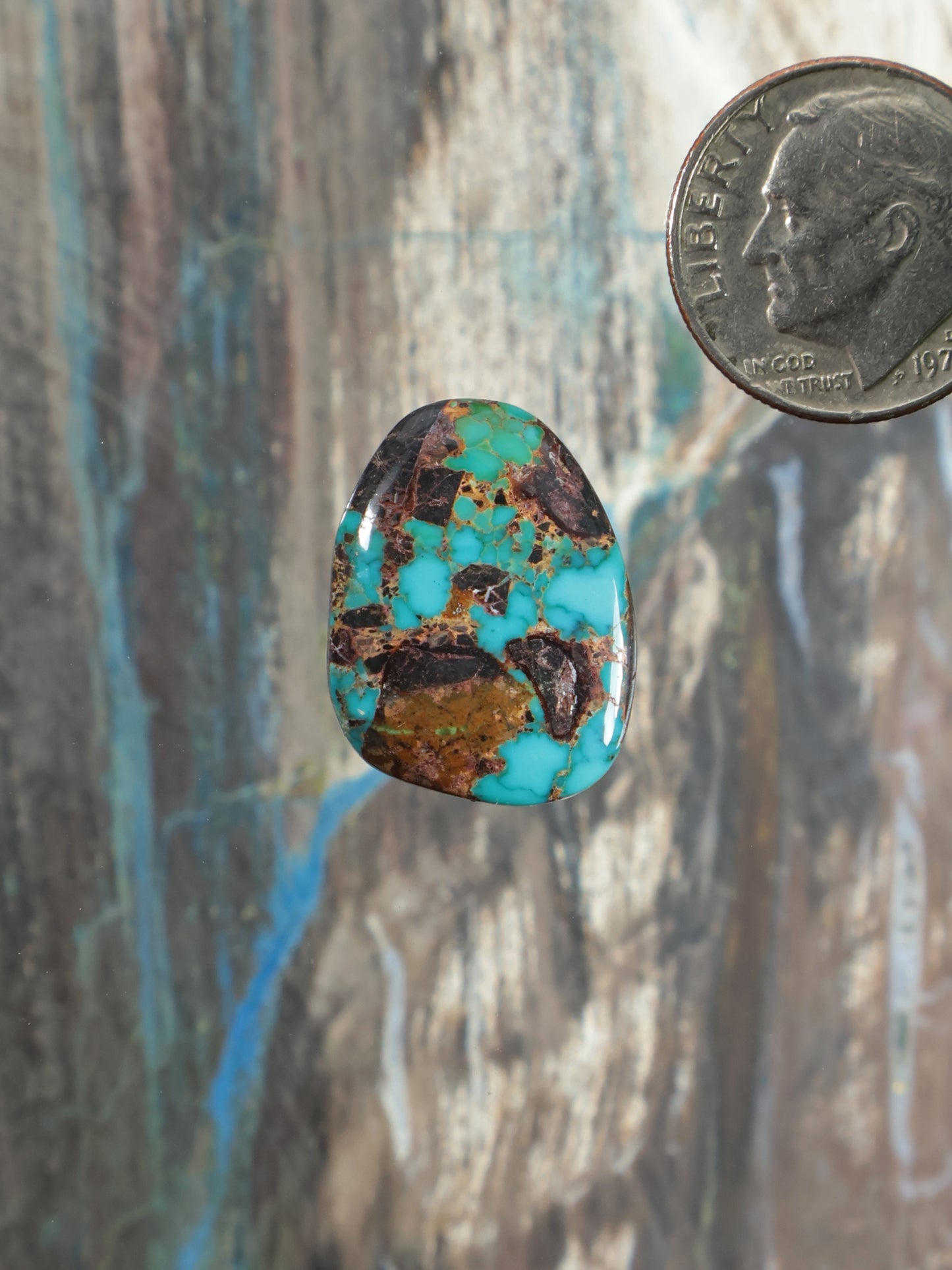 Oval turquoise cabochon gemstone with brown matrix and marbled pattern