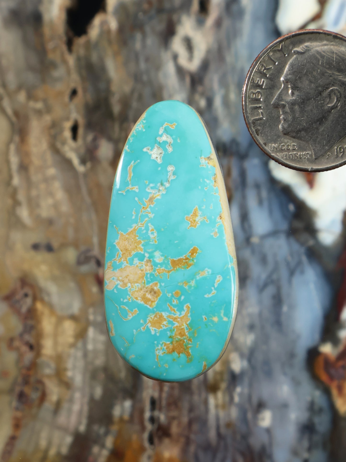 Turquoise cabochon gemstone with teardrop shape and gold-like matrix inclusions