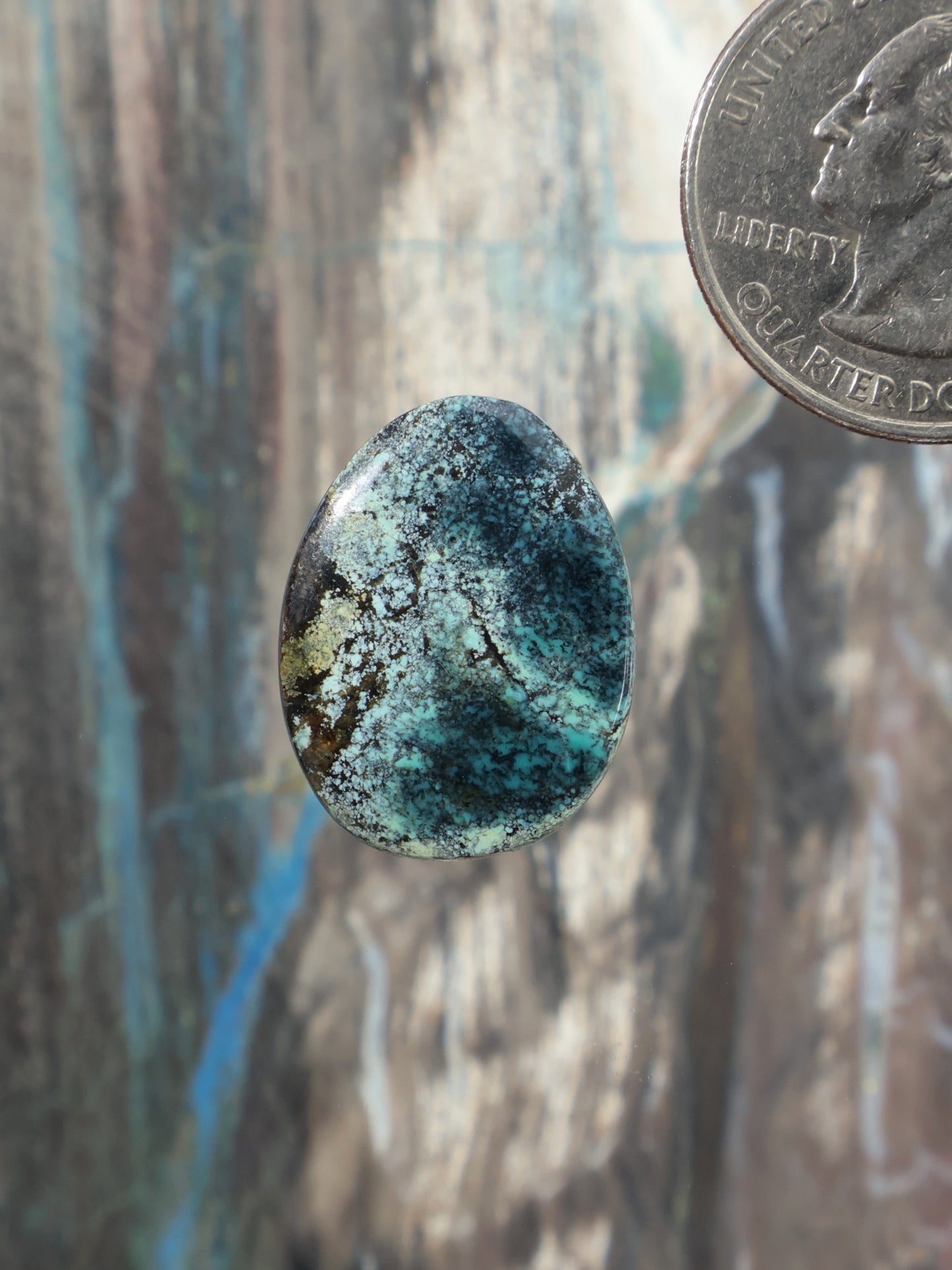 Turquoise oval cabochon gemstone with speckled blue-green surface