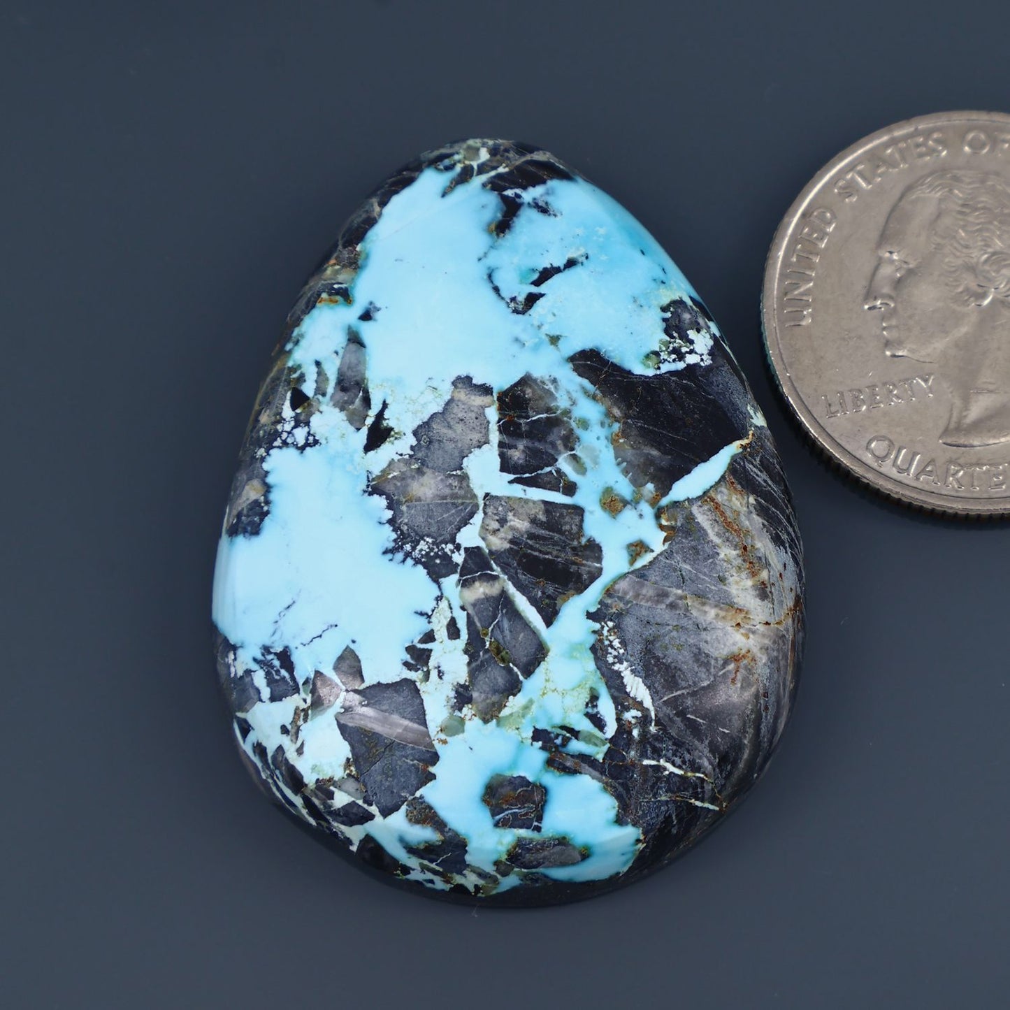 Oval turquoise cabochon gemstone with black matrix veining