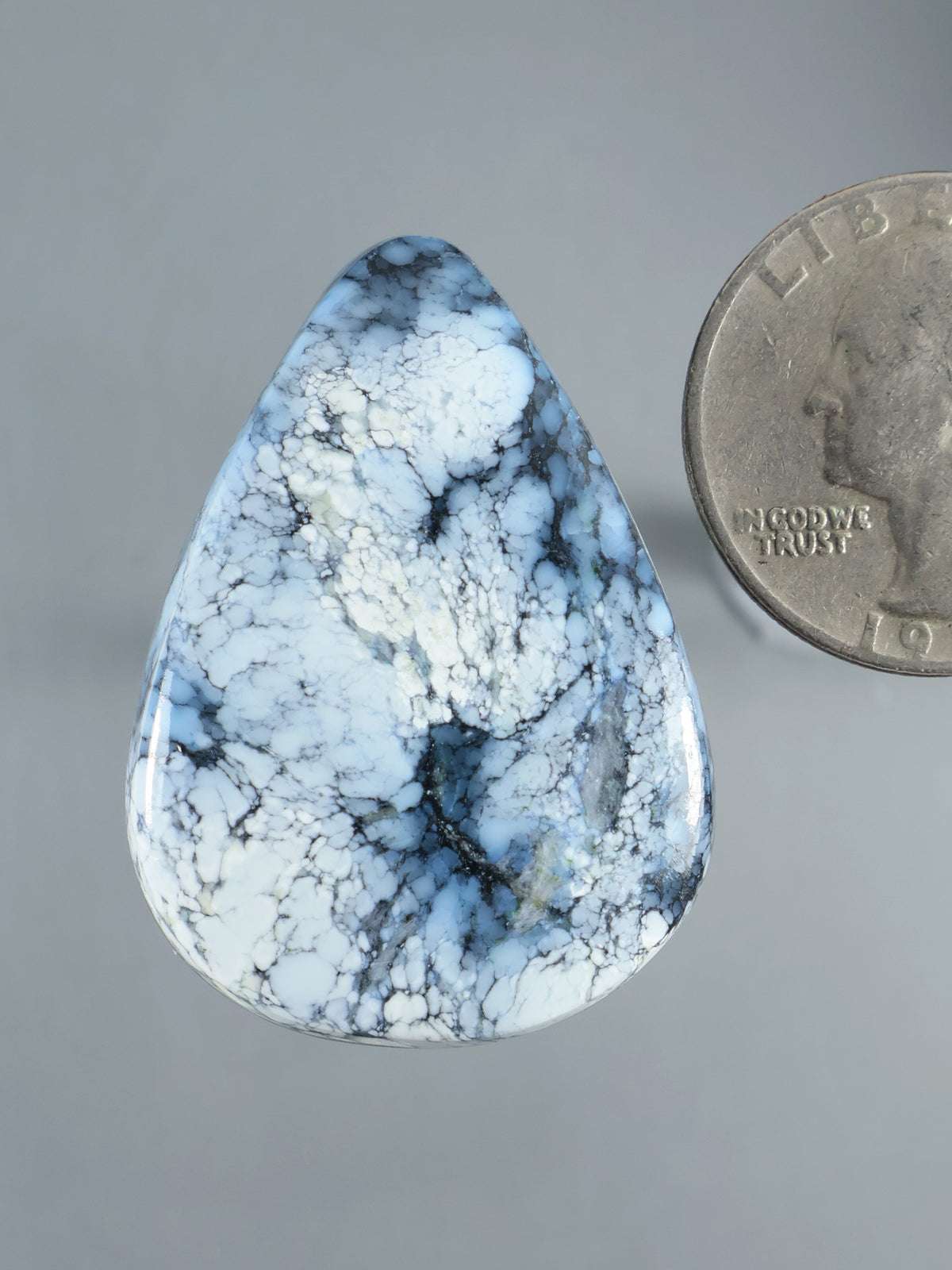 Blue and white marbled cabochon gemstone with a polished teardrop shape