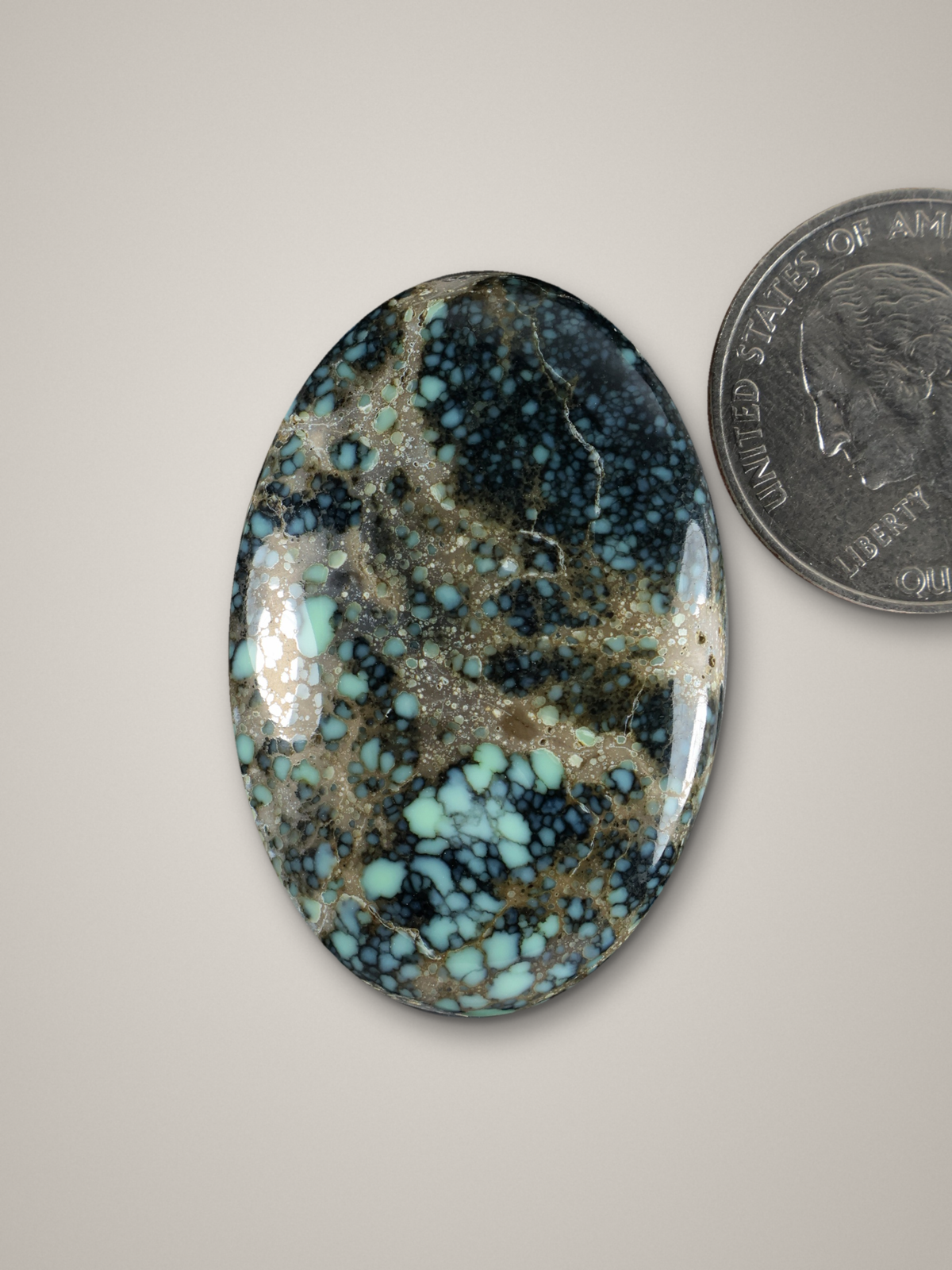 Oval blue-green variscite cabochon with speckled matrix and polished dome