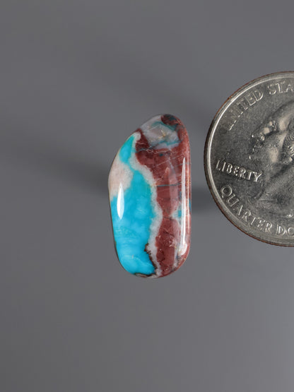 Oval turquoise cabochon with blue center and reddish-brown matrix, polished