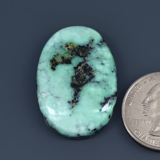 Oval  variscite cabochon with dark mineral veining and mottled inclusions