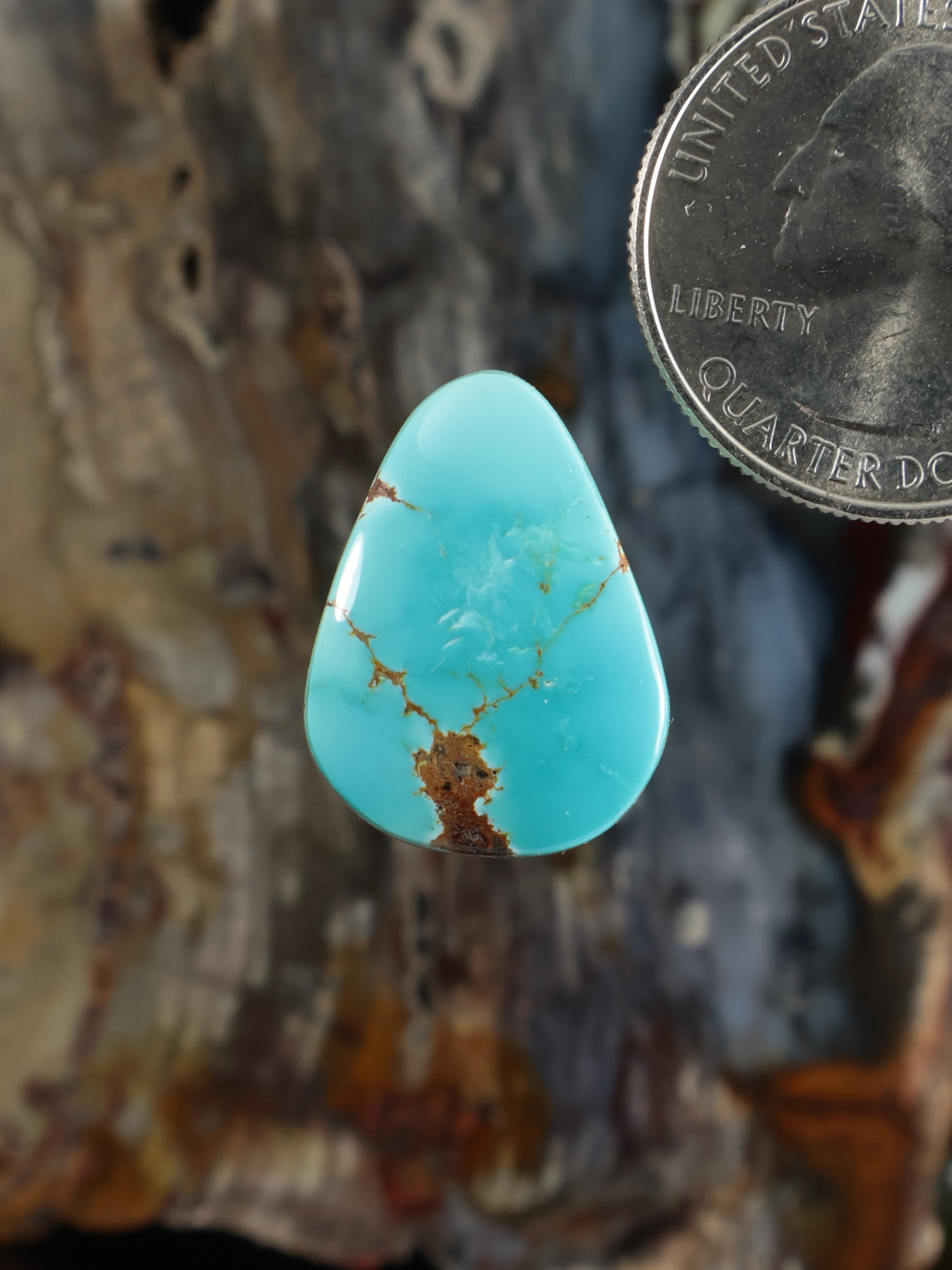 Turquoise cabochon gemstone in a teardrop shape with natural matrix veining