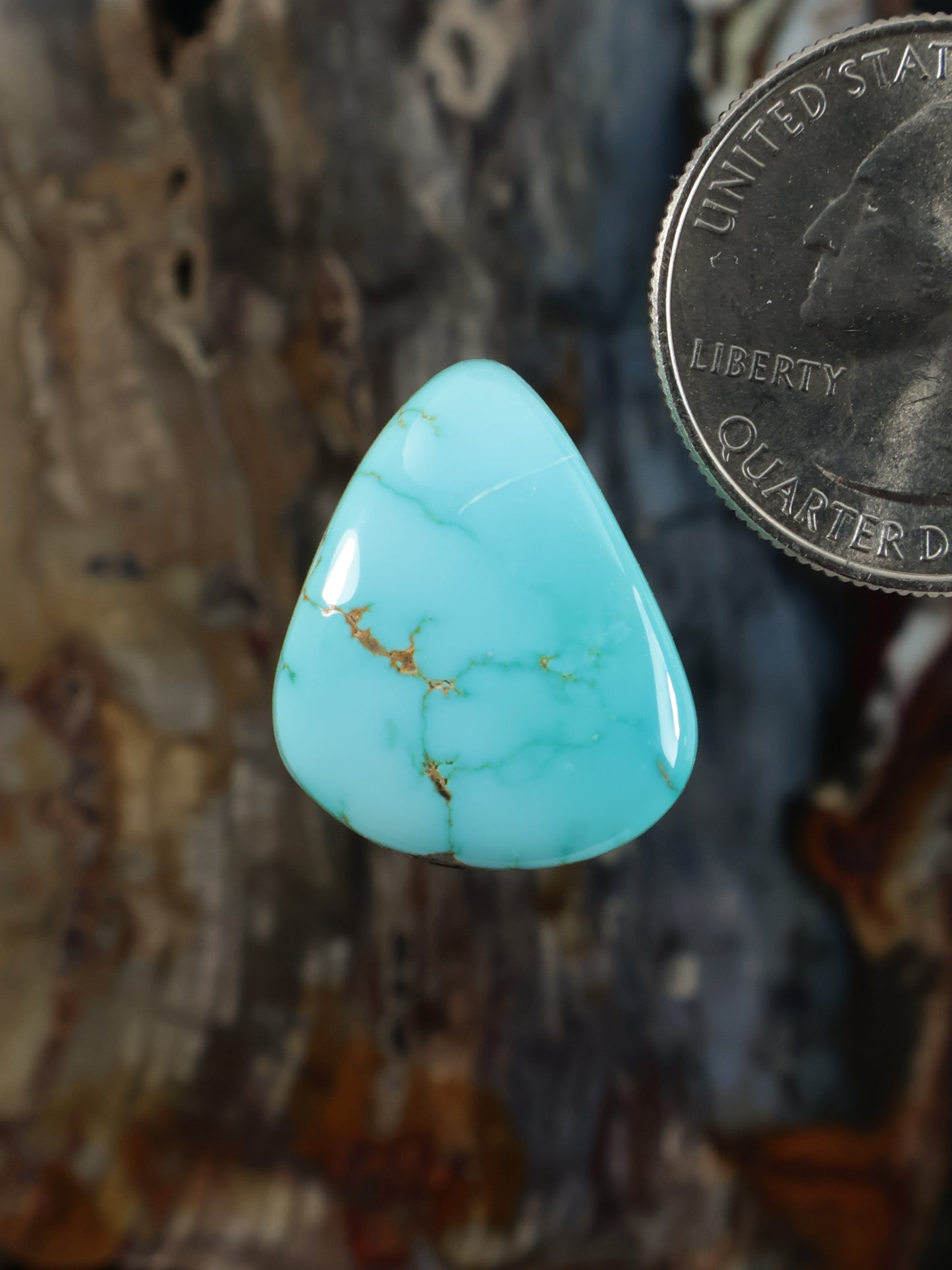 Turquoise teardrop cabochon with light-blue color and natural golden veining