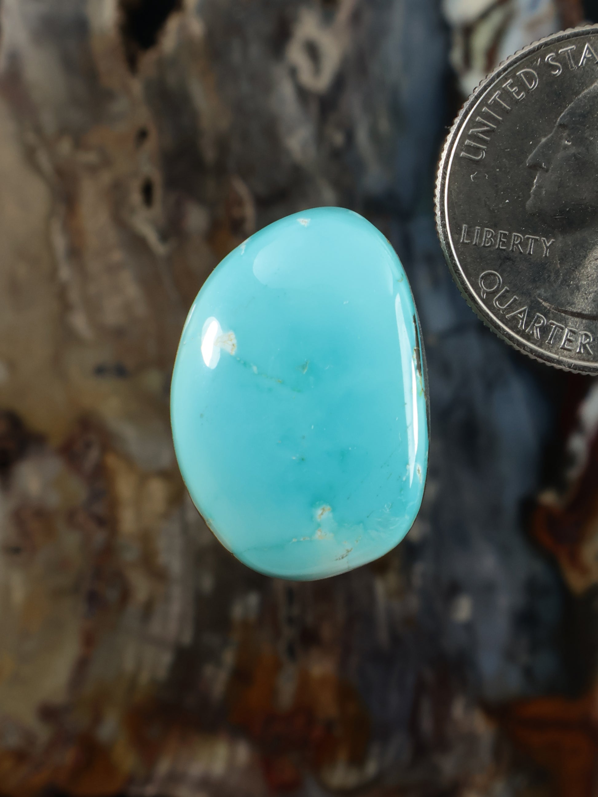 Oval turquoise cabochon gemstone with smooth polished face, light blue natural veining