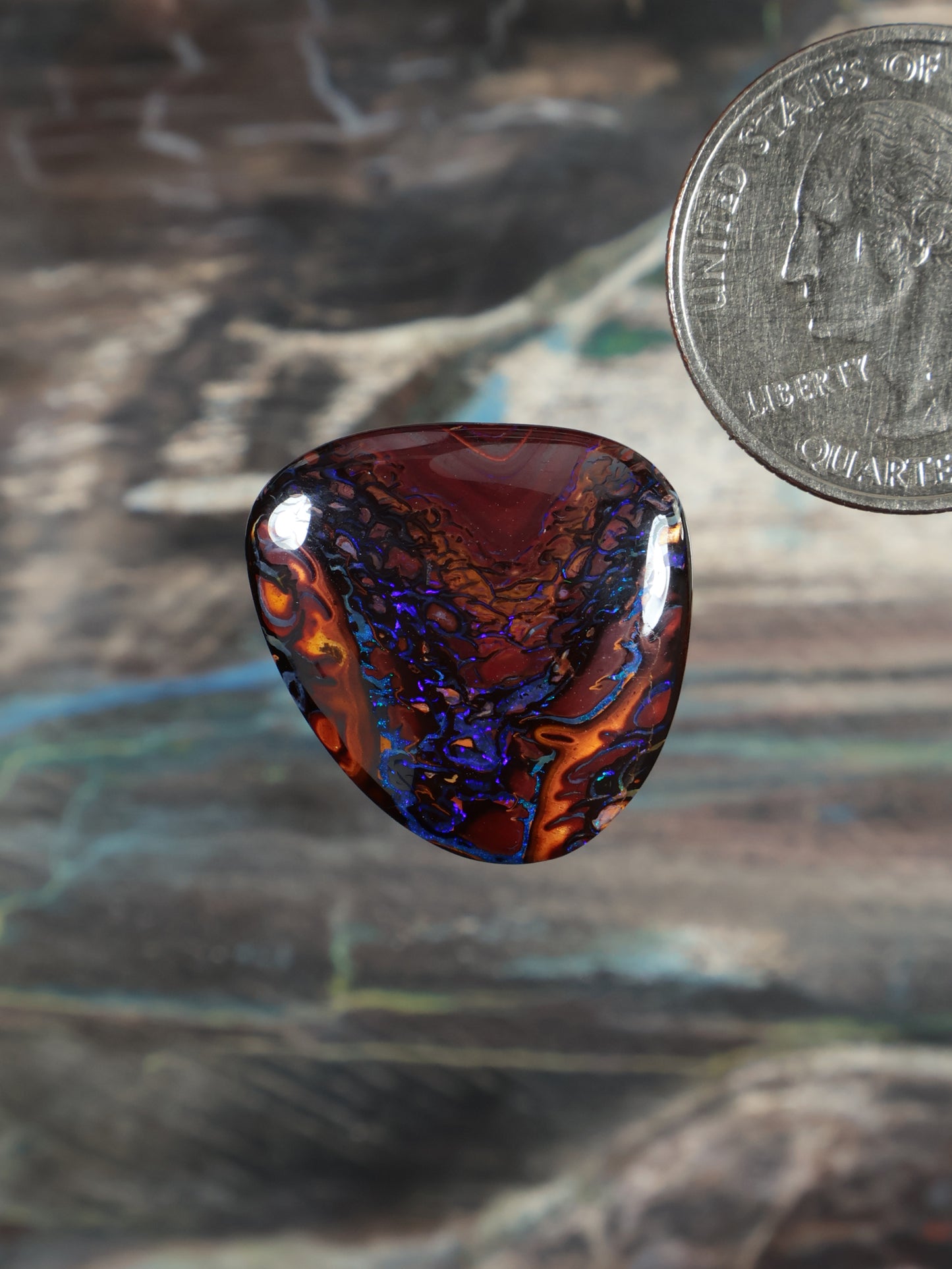 Yowah boulder opal cabochon, dark red and blue swirl pattern, polished oval