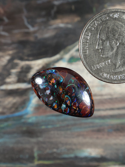 Dark boulder opal cabochon teardrop, domed surface with blue and turquoise iridescence