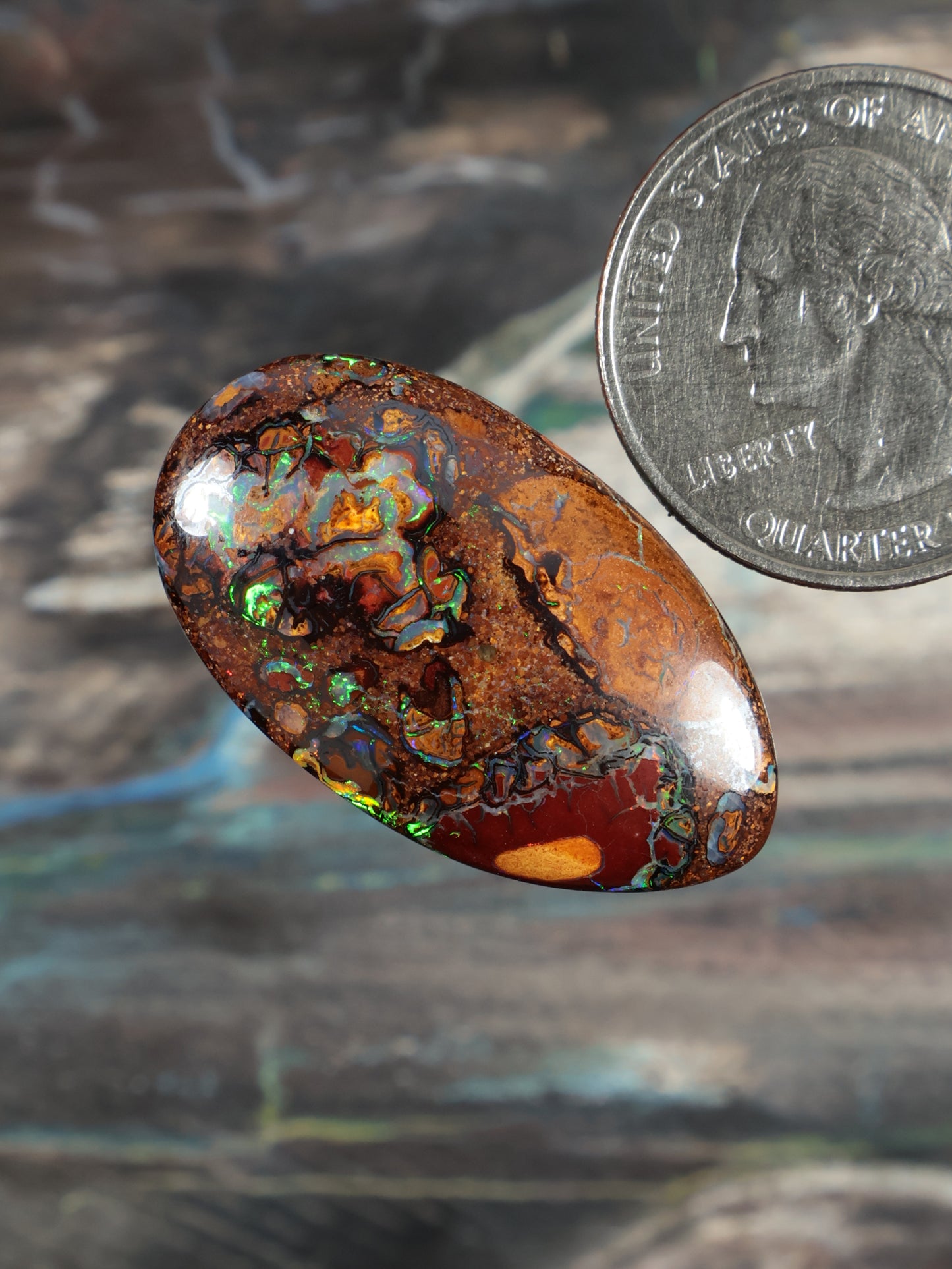 Oval boulder opal cabochon, deep orange-brown with green-blue fire inclusions