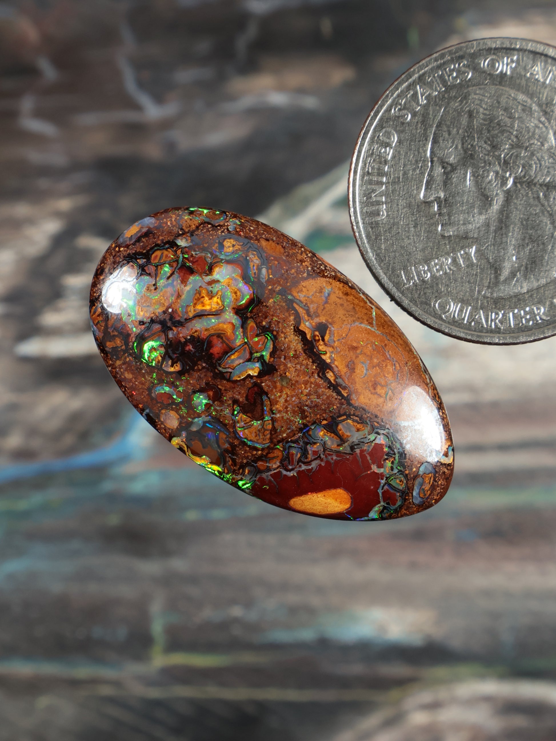 Oval boulder opal cabochon, deep orange-brown with green-blue fire inclusions