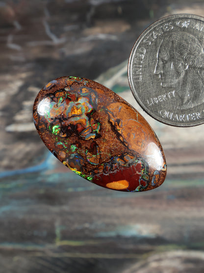 Oval boulder opal cabochon, deep orange-brown with green-blue fire inclusions