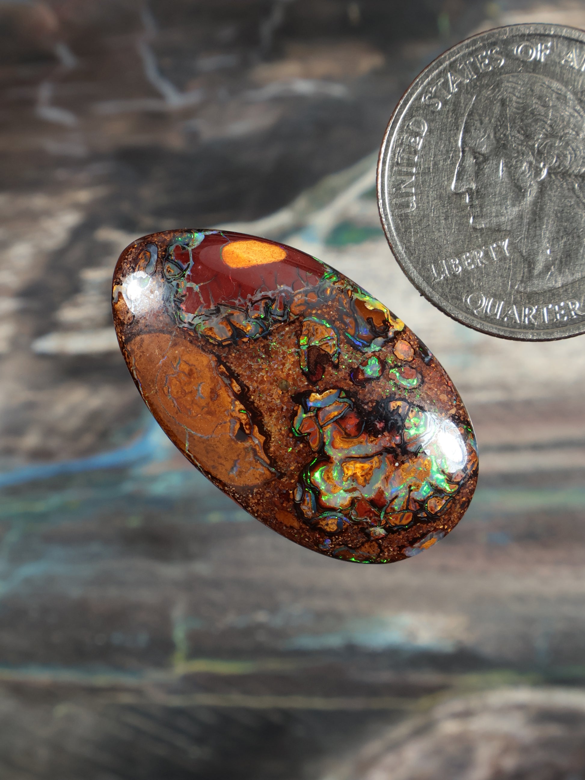 Oval boulder opal cabochon, warm orange base with bright blue-green flash