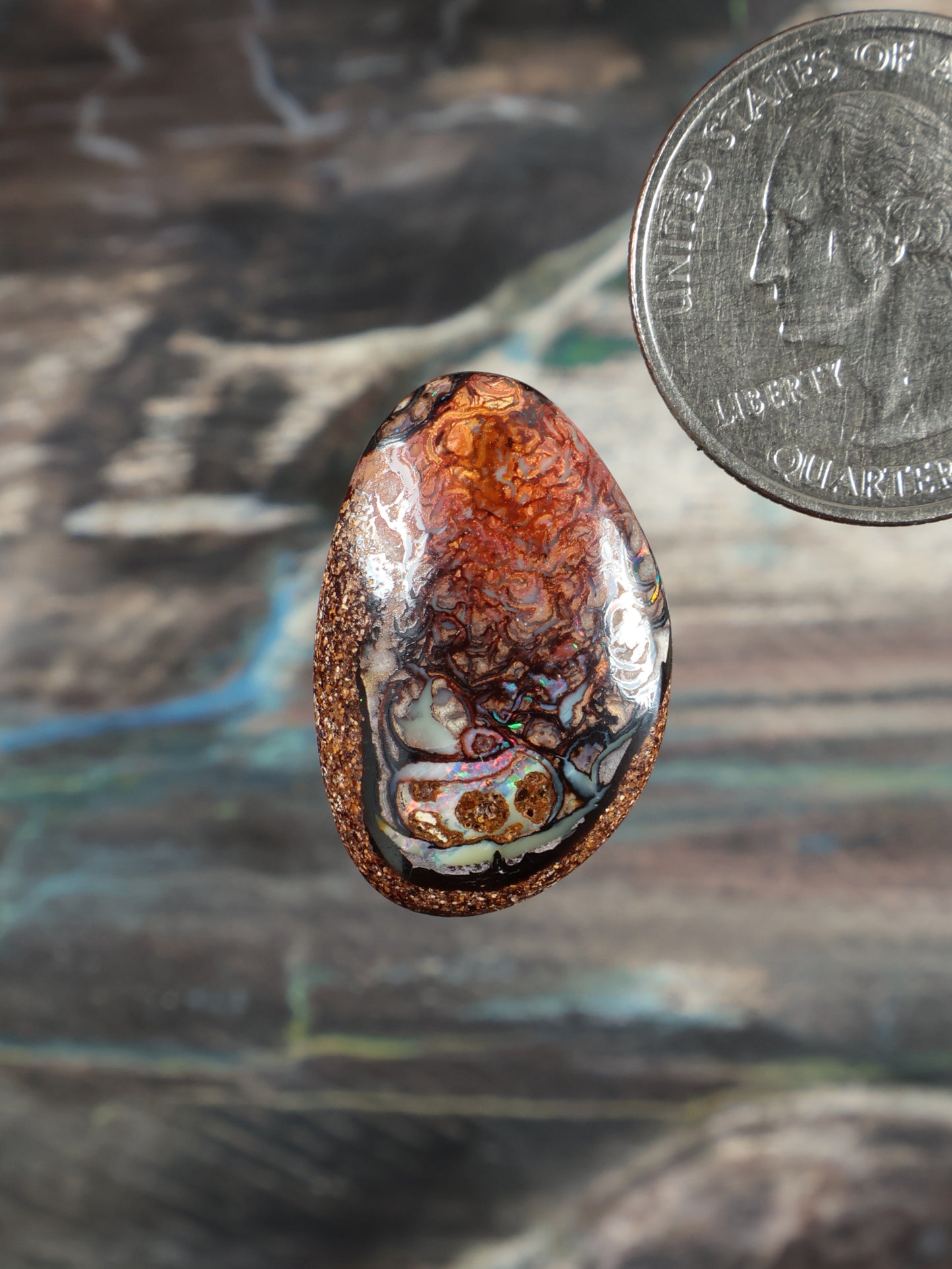 Boulder opal cabochon, oval; orange-brown stone with blue and teal swirls