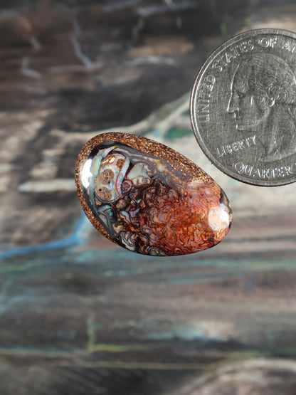 Boulder opal cabochon, oval; orange-brown base with white and blue marbling streaks