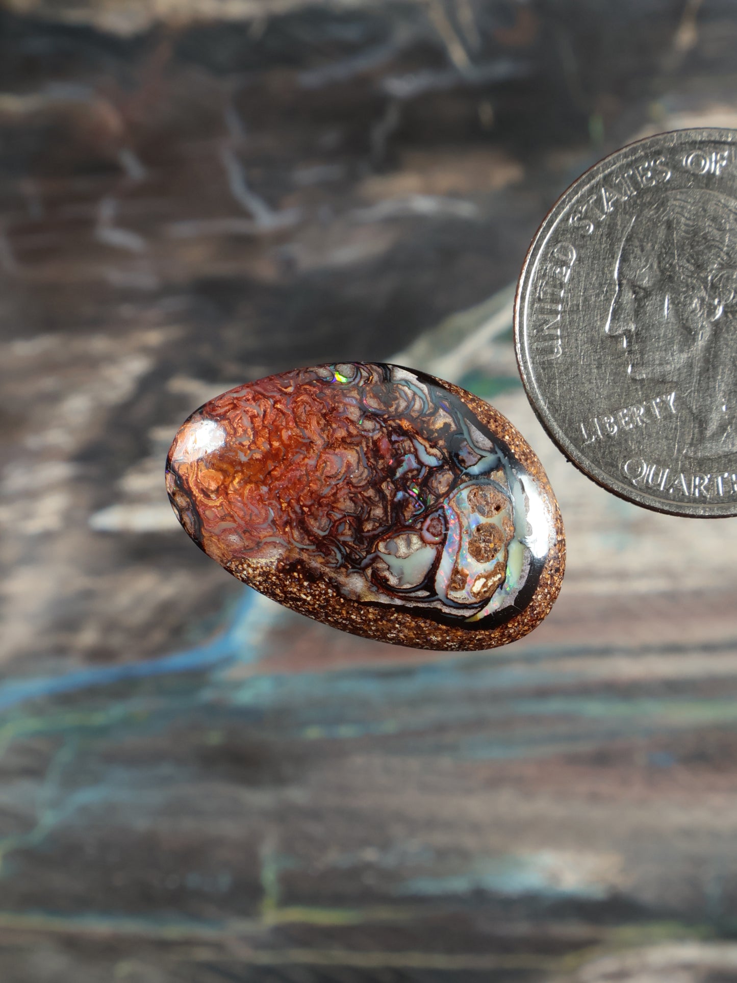 Boulder opal cabochon, oval; rich orange pattern with blue-green flashes and mottling