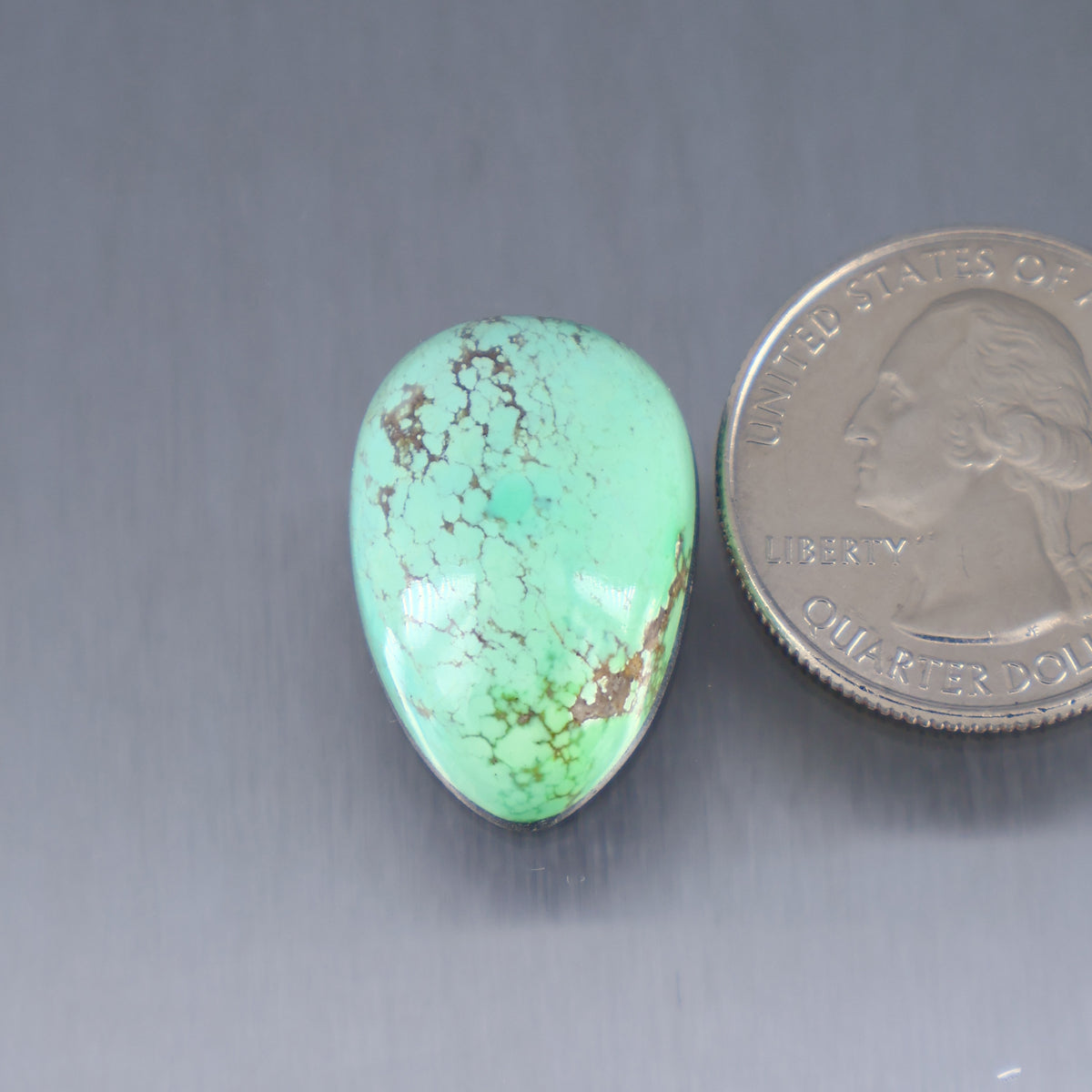 Turquoise cabochon gemstone with brown matrix veining; oval shape