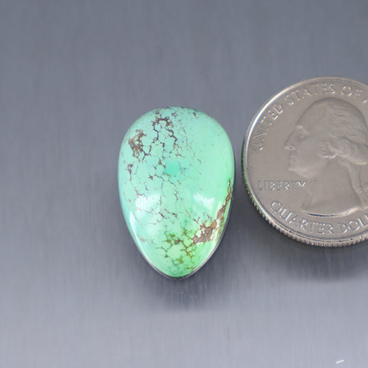 Turquoise cabochon gemstone with brown matrix veining; oval shape