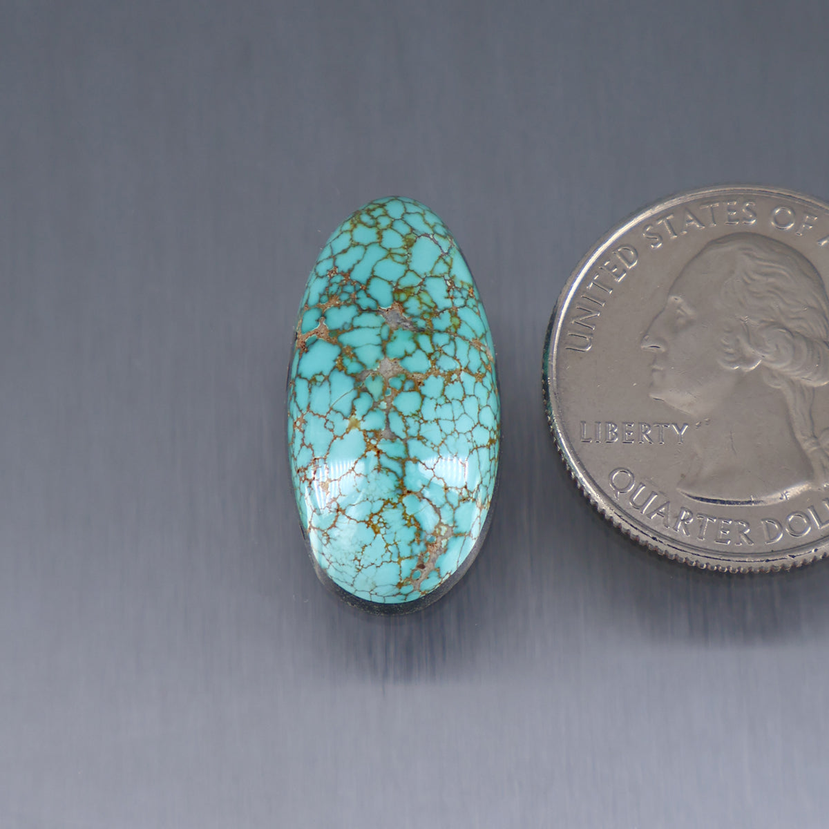 Turquoise oval cabochon with gold matrix webbing, polished stone.