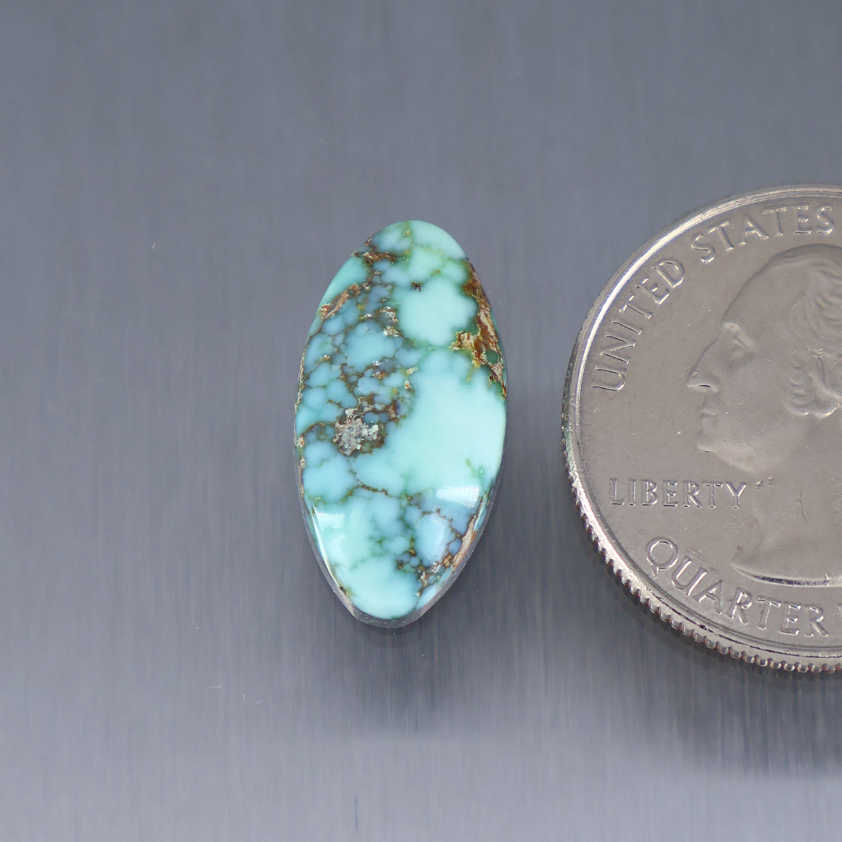 Oval turquoise cabochon gemstone with brown matrix veining and small center cluster
