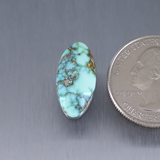 Oval turquoise cabochon gemstone with brown matrix veining and small center cluster
