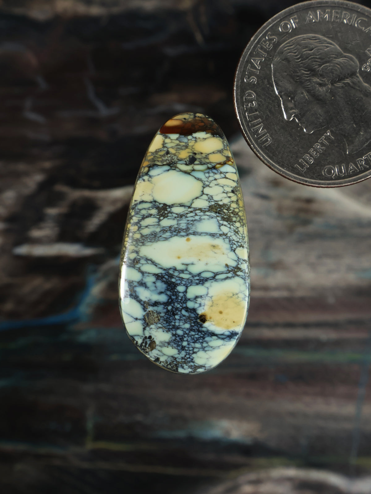 Oval cabochon gemstone with blue and yellow veining