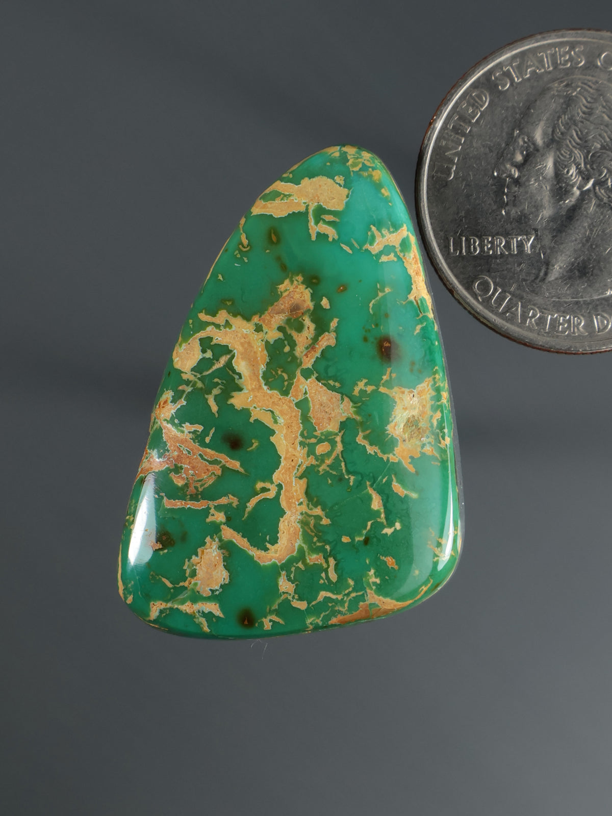 Triangular green cabochon gemstone with gold map-like marbling