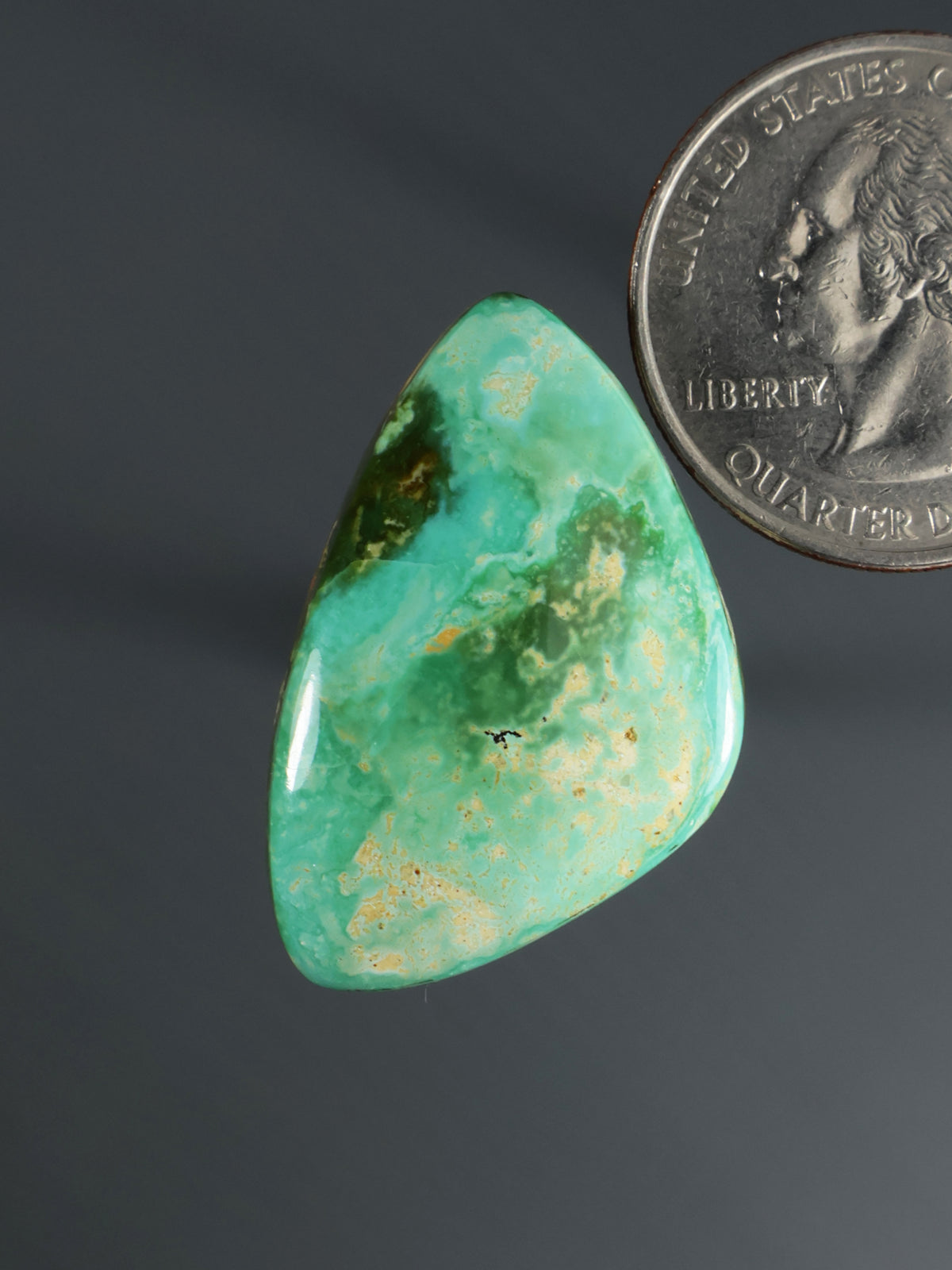 Green teardrop cabochon gemstone with yellow-green mottling