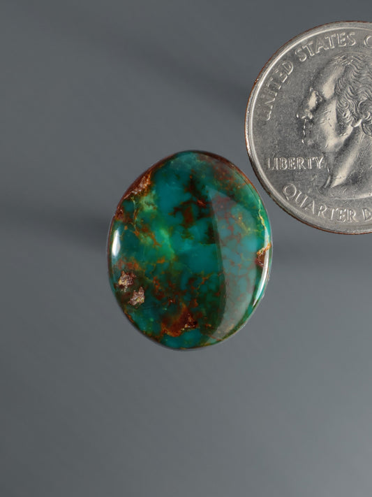 Oval turquoise cabochon gemstone with green-blue color and natural matrix