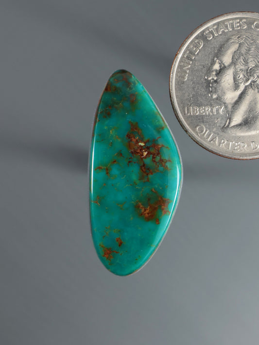 Turquoise cabochon gemstone, oval with reddish matrix, polished surface