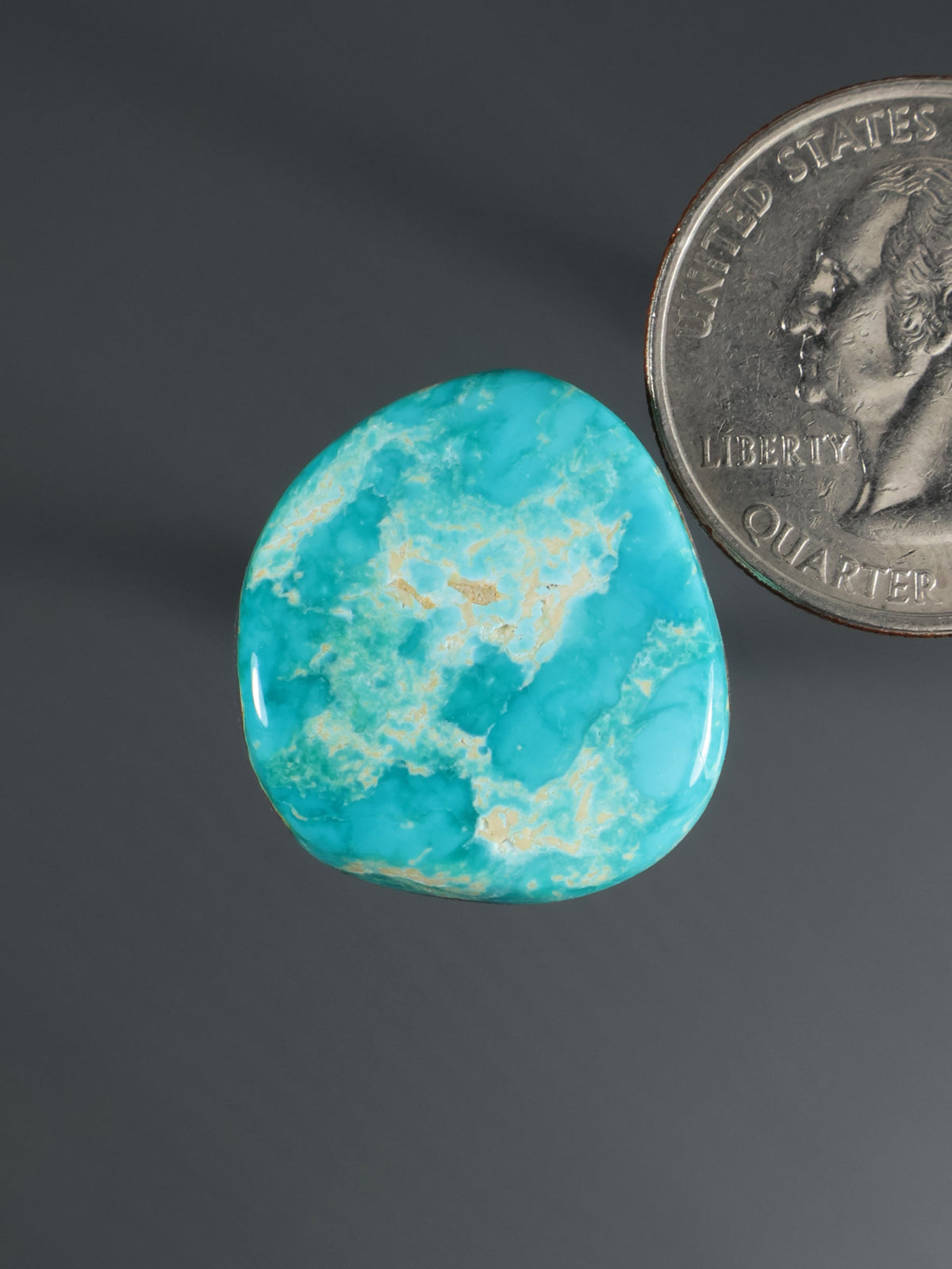 Turquoise oval cabochon gemstone with blue-green veining, close-up
