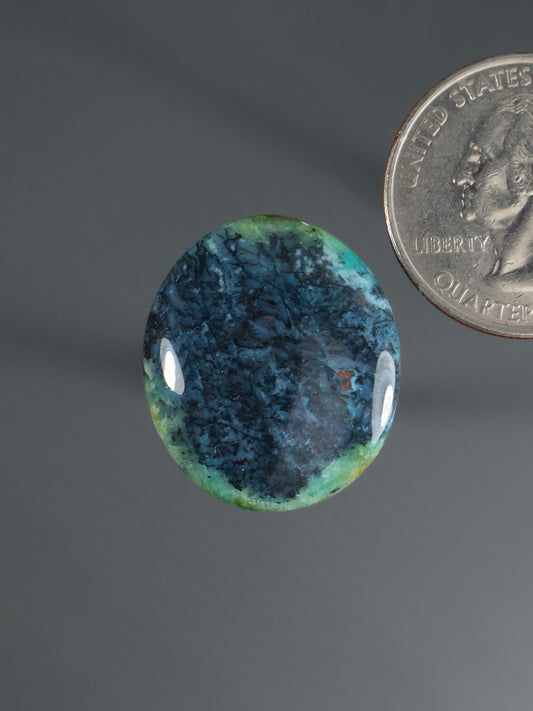 Round cabochon gemstone with blue-green swirling pattern