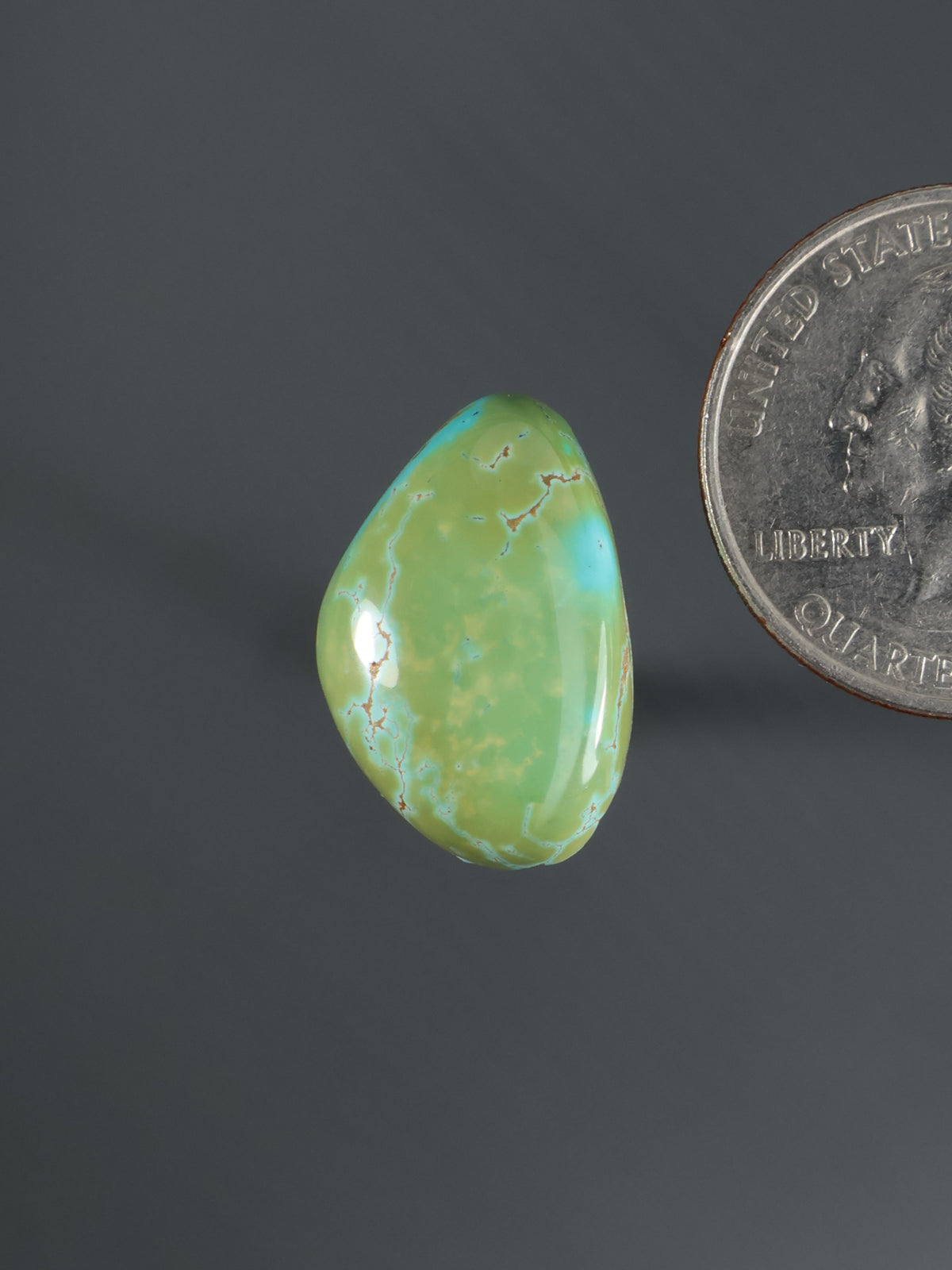 Oval teal-green cabochon gemstone with polished domed surface