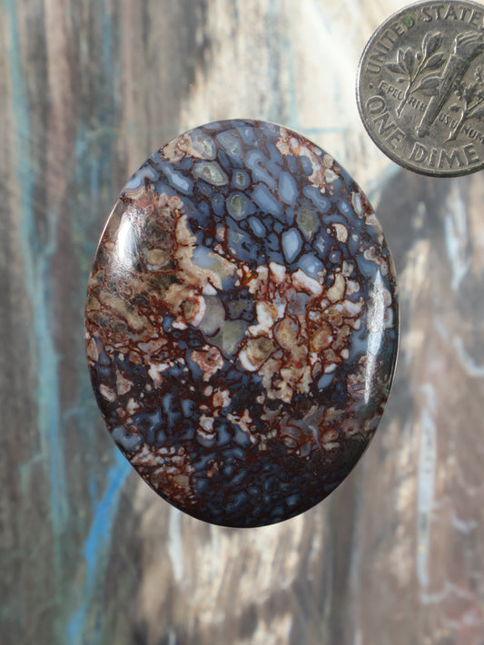 Oval gembone cabochon with blue, brown, and tan mottled stone pattern