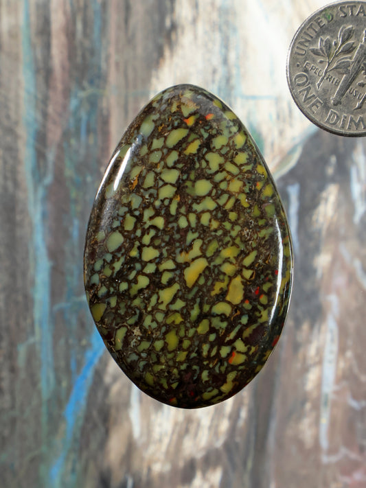 Oval gembone cabochon with green and yellow web-like stone pattern
