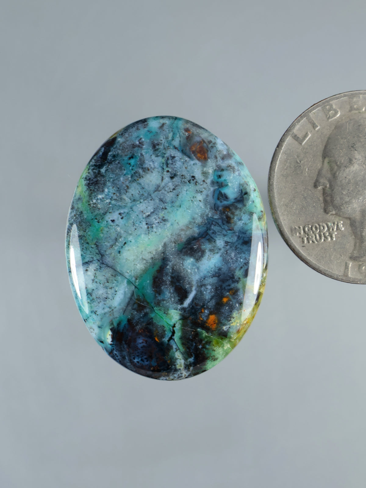 Oval blue opalized petrified wood cabochon with teal-green and dark veining