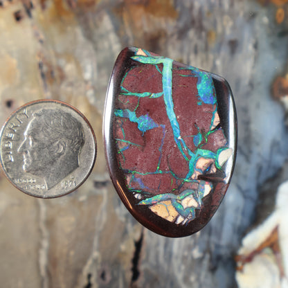 Oval boulder opal cabochon with red stone and teal-blue veining, polished domed face
