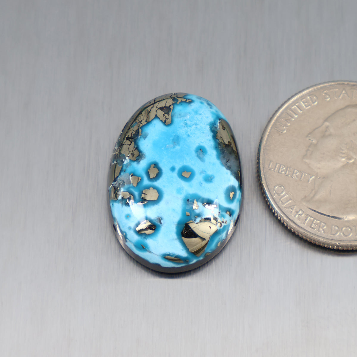 Blue turquoise oval cabochon with dark matrix spots and gold veining