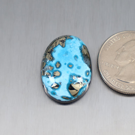 Blue turquoise oval cabochon with dark matrix spots and gold veining