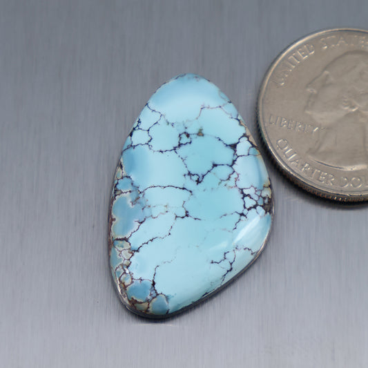 Turquoise cabochon gemstone, light blue with dark vein webbing, teardrop shape