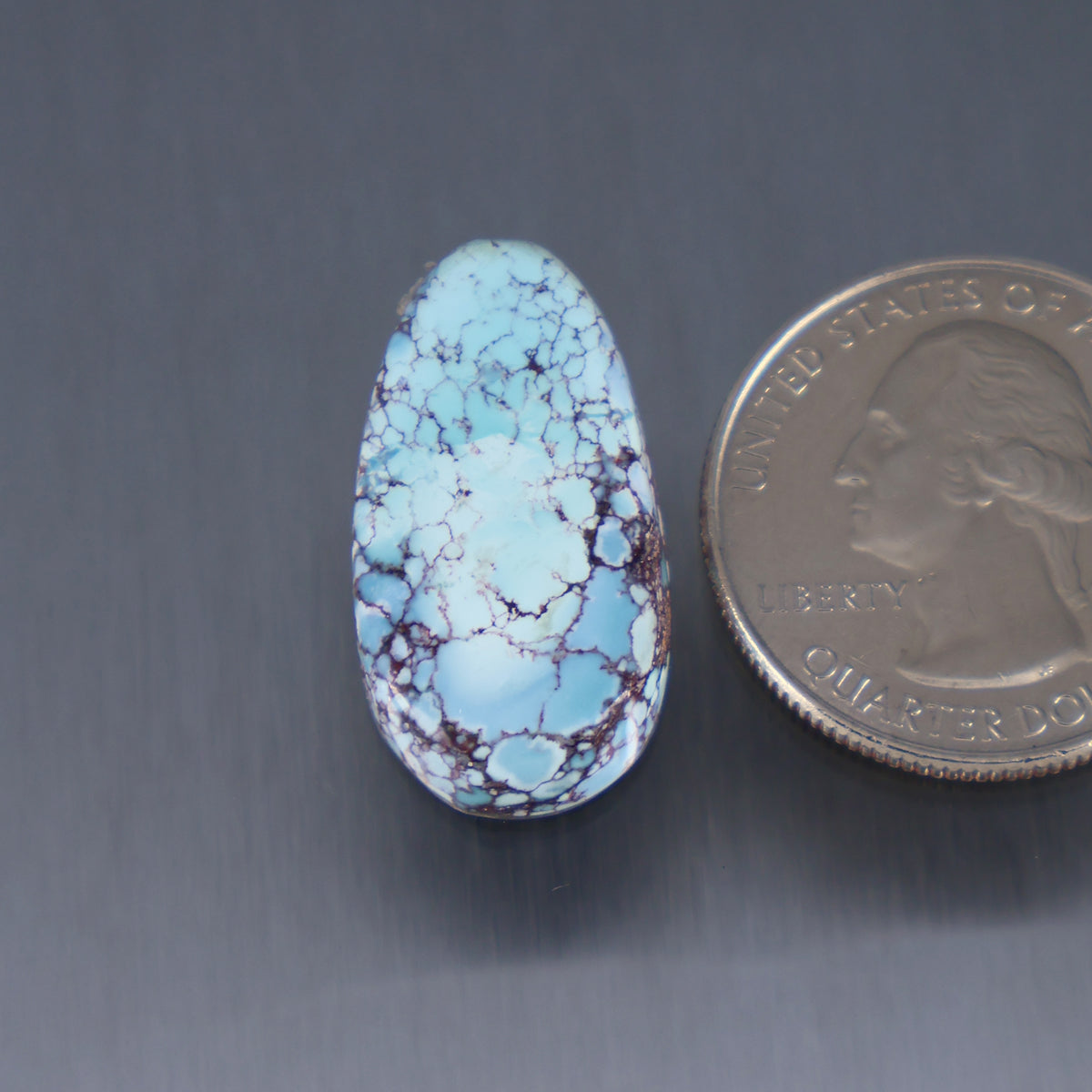 Oval turquoise cabochon with blue color and webbed matrix pattern, polished dome