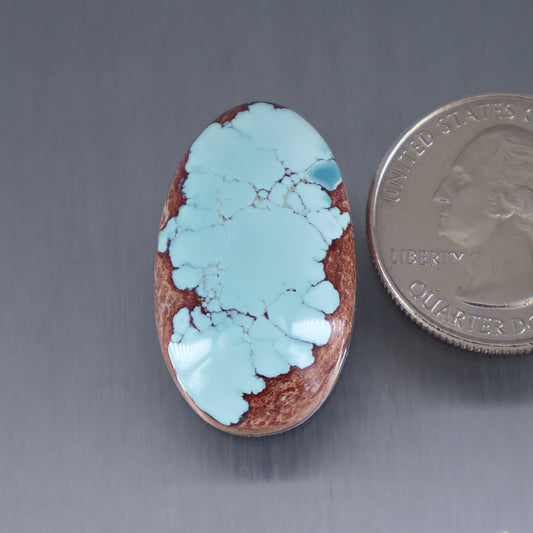 Oval turquoise cabochon with blue veining and reddish brown matrix, polished