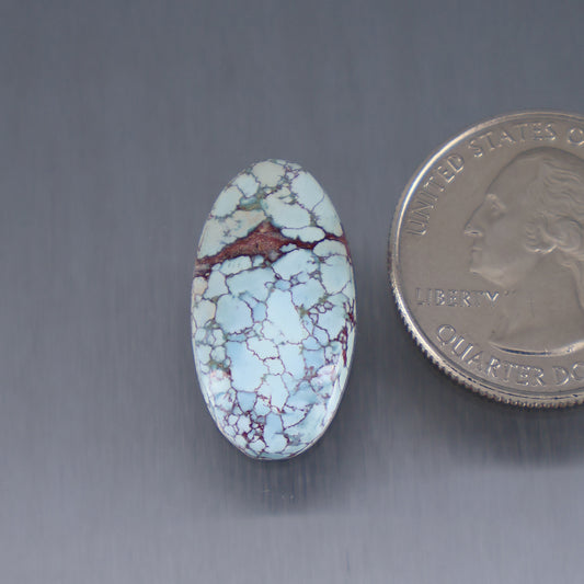 Oval turquoise cabochon with white and blue matrix and reddish-brown patch