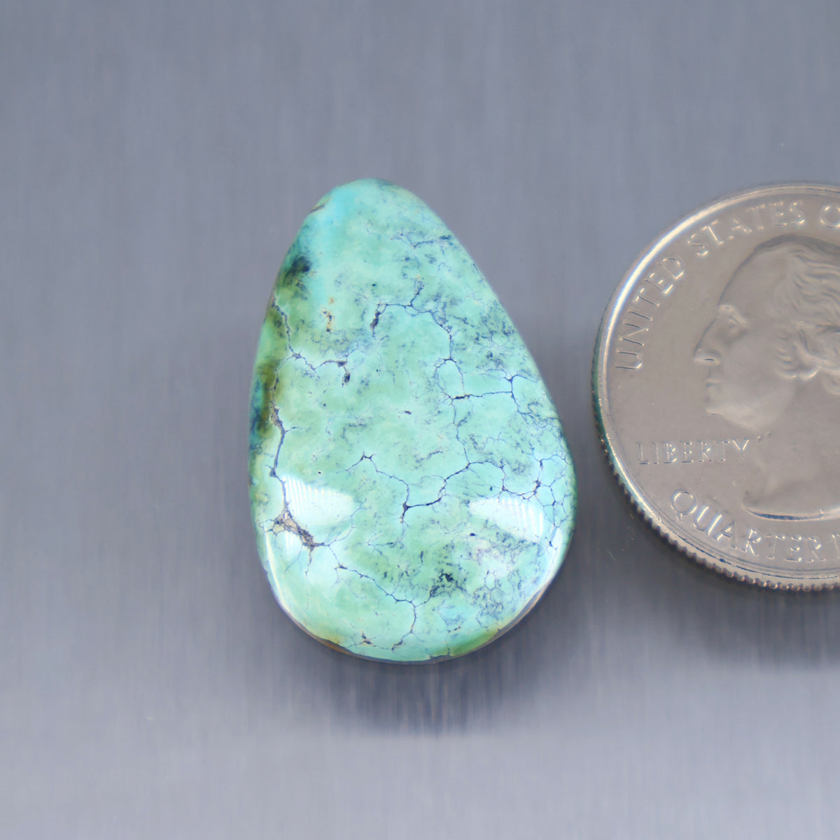 Turquoise cabochon gemstone, teardrop shape with natural veining details